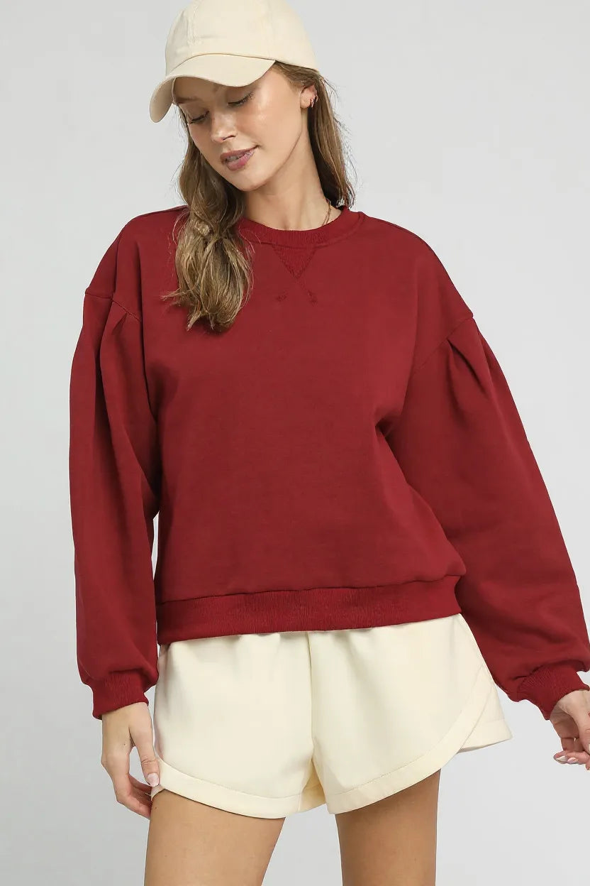 Umgee round neck sweatshirt with pleated detail, featuring a comfortable fit and stylish design in soft fabric.