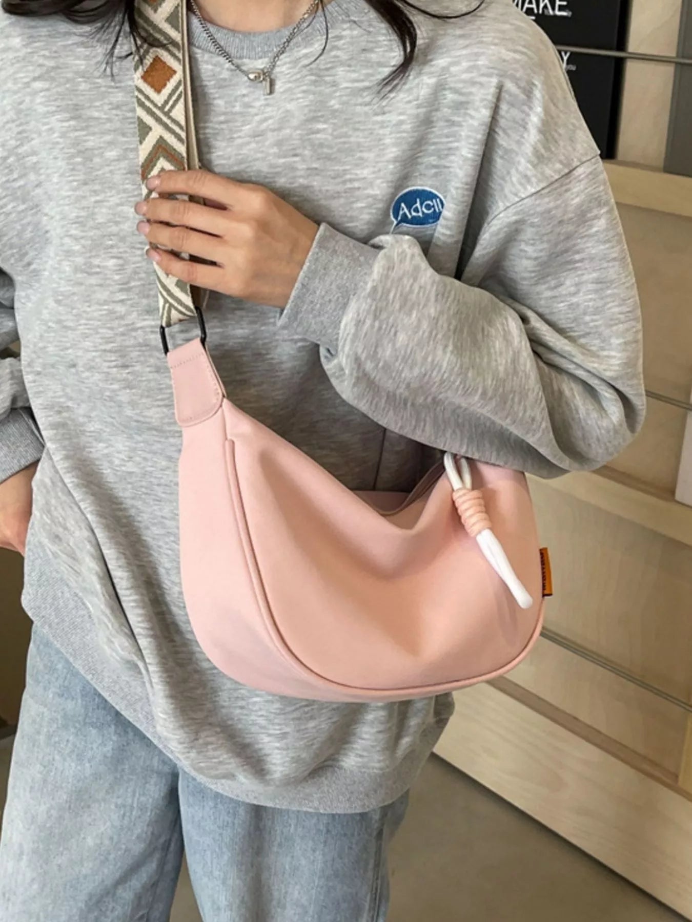 Geometric strap crossbody bag with structured design and trendy patterns, featuring adjustable strap and compact size.