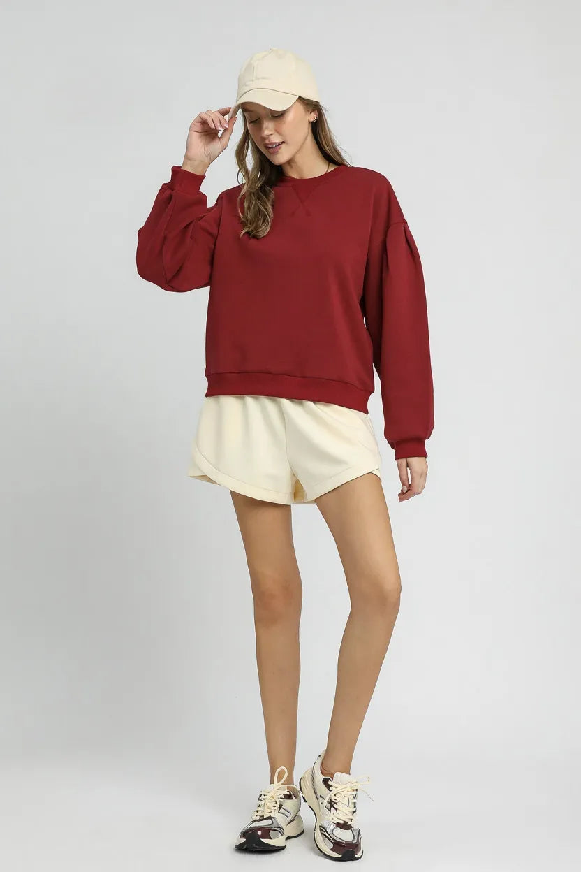 Trendsi Umgee round neck sweatshirt featuring pleated detail, soft fabric, and relaxed fit for casual comfort.