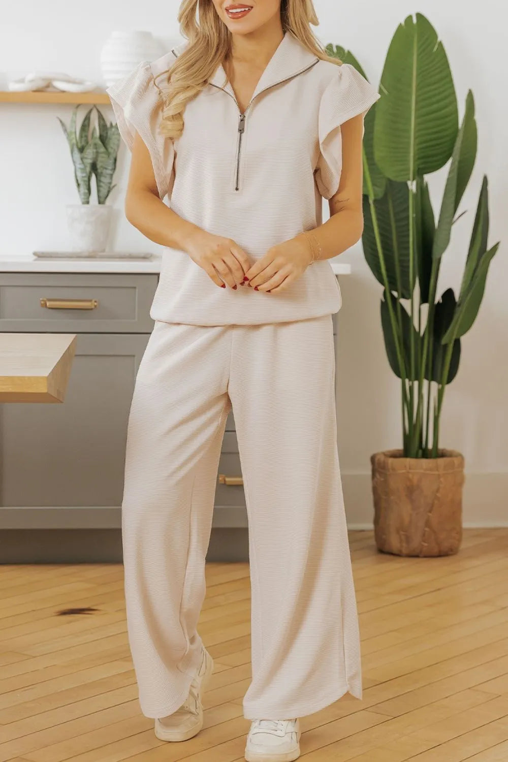 Beige textured ruffled sleeve zipped top paired with wide-leg pants set by Trendsi, shown on a mannequin.