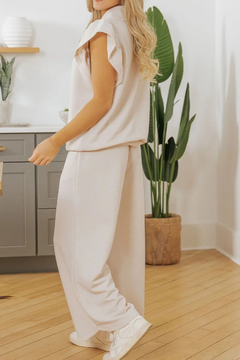 Beige textured ruffled sleeve zipped top and wide-leg pants set by Trendsi, featuring stylish ruffle details and a modern silhouette.