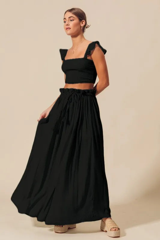 Black SO ME smocked crop top and flowy maxi skirt set by Trendsi, displayed on a model with ruffled details and relaxed fit.