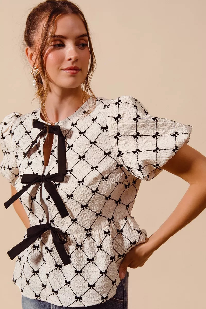 Ivory woven peplum top by Trendsi with bow texture and contrasting tie detail, stylish and lightweight for casual or dressy wear.