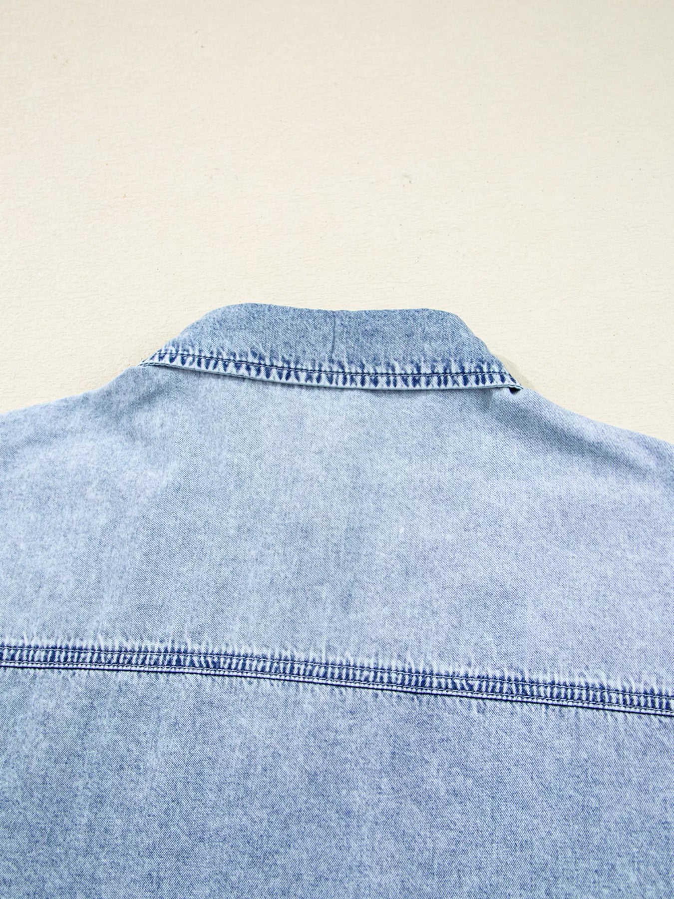 Light blue denim shirt dress with chest pockets, raw hem, and a loose fit from Trendsi, styled as casual wear.
